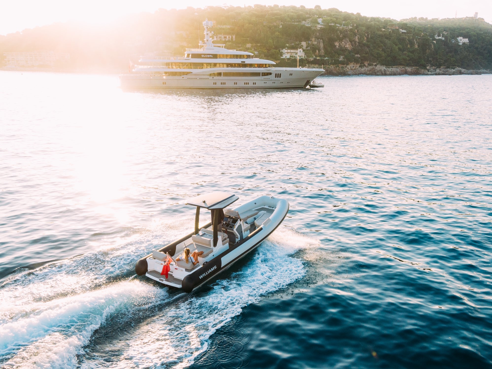 A luxury jet tender by Williams Jet Tenders gliding through the water at sunset, leaving a trail of wake behind.